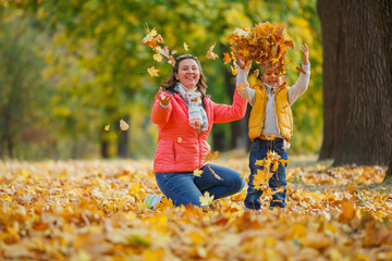 Adorable boy with his mother in autumn park