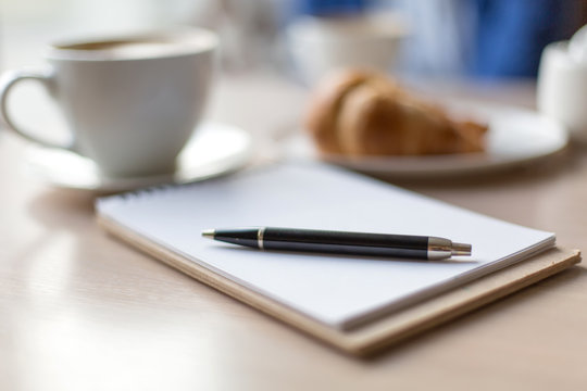 coffee , notebook and croissant on a wooden table