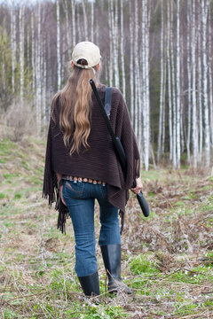 Woman hunter with gun walking in the forest