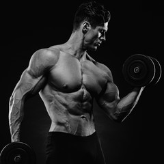 Handsome power athletic man in training pumping up muscles with