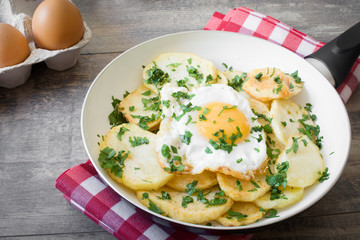 Potatoes, fried eggs and parsley in a frying pan