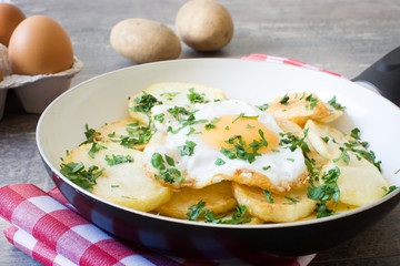 Potatoes, fried eggs and parsley in a frying pan