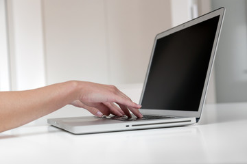 Close up of woman's hands typing on a laptop.