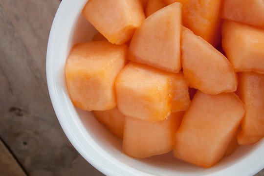 closeup melon slice in white dish with wood table background