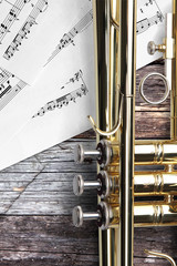 Trumpet with sheet music on rusty wooden boards