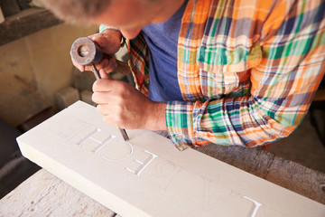 Stone Mason At Work On Carving In Studio