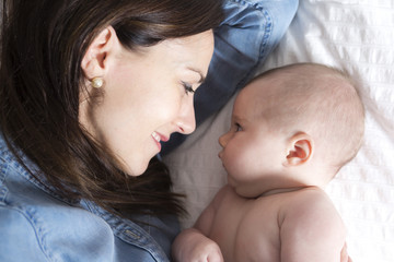 baby and mother in white bed taking good time