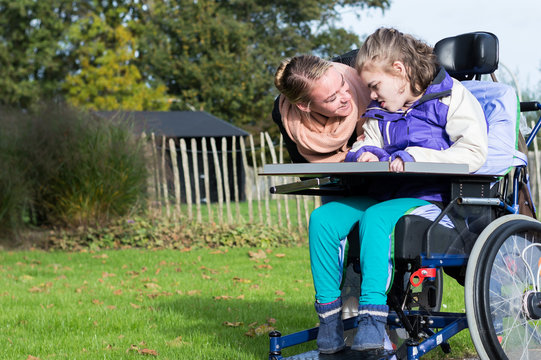 Disabled girl in a wheelchair relaxing outside / Disabled girl in a wheelchair relaxing outside with help from a care assistant