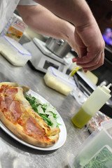 Closeup hand of chef baker in white uniform making pizza at kitchen
