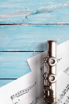 Old flute with sheet music on blue wooden boards
