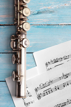 Old flute with sheet music on blue wooden boards