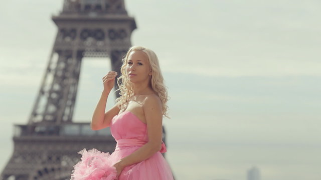 Tender girl in a pink fairy long dress posing near the Eiffel Tower in Paris