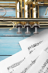 Trumpet with sheet music on blue wooden boards