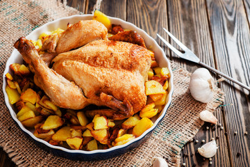 
Baked chicken with baked potatoes , apples , garlic and spices on a wooden background