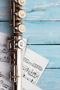 Old flute with sheet music on blue wooden boards