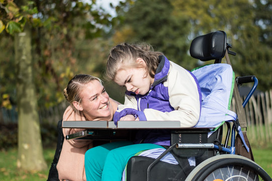 Disabled girl in a wheelchair relaxing outside / Disabled  girl in a wheelchair relaxing outside together with a care assistant