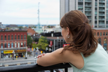 Fototapeta na wymiar Woman looks out to city from balcony