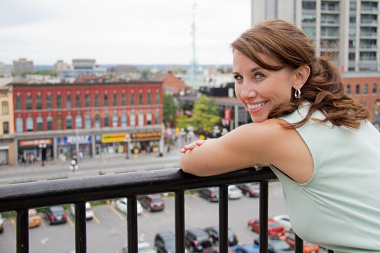 Smiling attractive young woman with city background looking at c