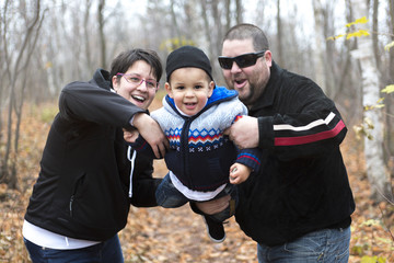 Naklejka premium Autumn portrait of happy young cheerful parents with child. 