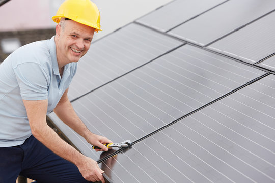 Engineer Installing Solar Panels On Roof Of House