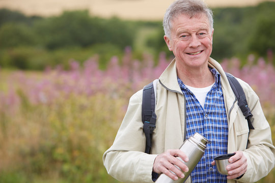 Senior Man Pouring Drink From Flask On Walk