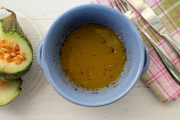 Pumpkin yellow soup in blue dish, slice of pumpkin on plaid table cloth, spoon and fork 