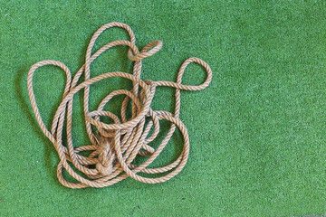 thick tangled rope on the playing field. natural sisal rope of lies on green artificial surface...