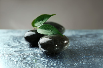Composition of pebbles with leaf on the table against grey background