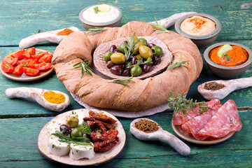 Assorted antipasti with olives, cheese, salami, bread on wooden table