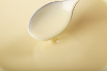 Background of condensed milk and a spoon in a bowl, close-up