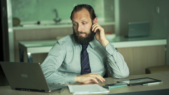 Bored, young businessman sitting by table in office
