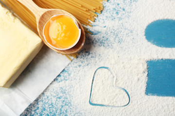 Heart of flour and pasta on color wooden background