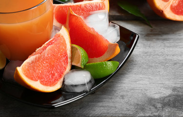 Citrus juice and fresh fruits on black plate