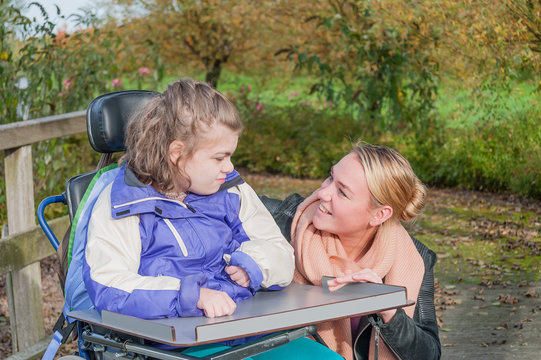 Disabled girl in a wheelchair relaxing outdoors / Disabled girl in a wheelchair relaxing outdoors together with a care assistant