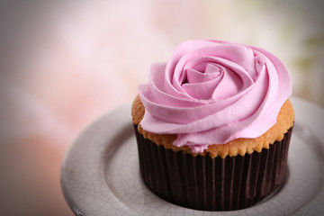 Tasty cupcake on stand, on light background