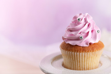 Tasty cupcake on stand, on light background