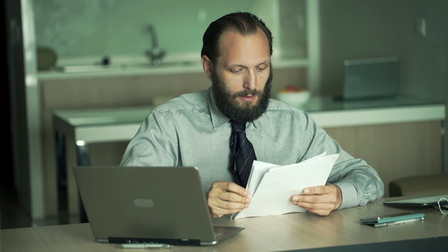 Young businessman working with laptop and documents in office
