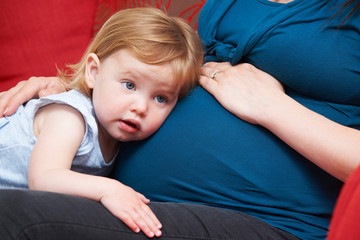 Young Girl Listening To Pregnant Mother's Tummy