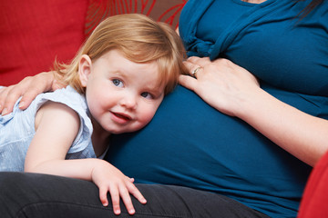 Young Girl Listening To Pregnant Mother's Tummy