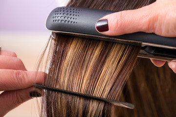 Hairstylist straightening the hair of a client