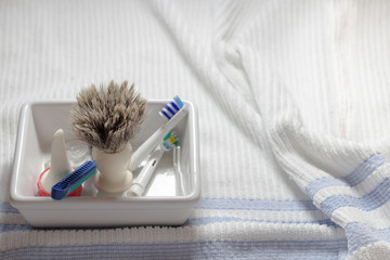 Shaving brush and razor in soap dish withblue and white towel.