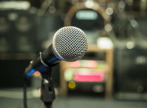 Selective focus on microphone with blurry music studio backgroun