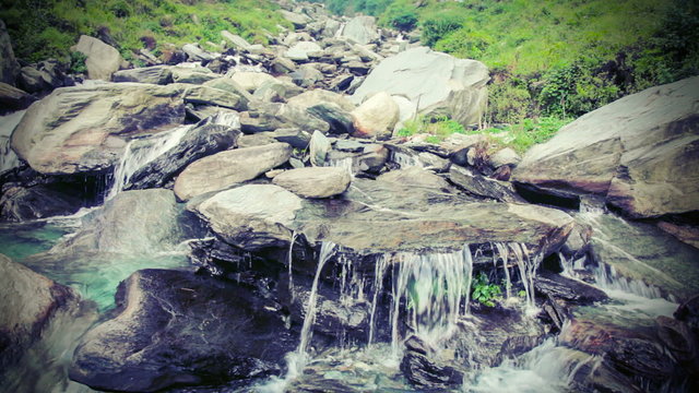 Vintage retro hipster style color graded video of cascade of Bhagsu waterfall in Himalayas. Bhagsu, Himachal Pradesh, India. Polarizer filter used