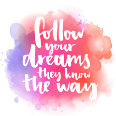 Follow your dreams, they know the way. Inspirational quote about life and love.  Modern calligraphy text, handwritten with brush on pink and orange watercolor splash background with bokehs
