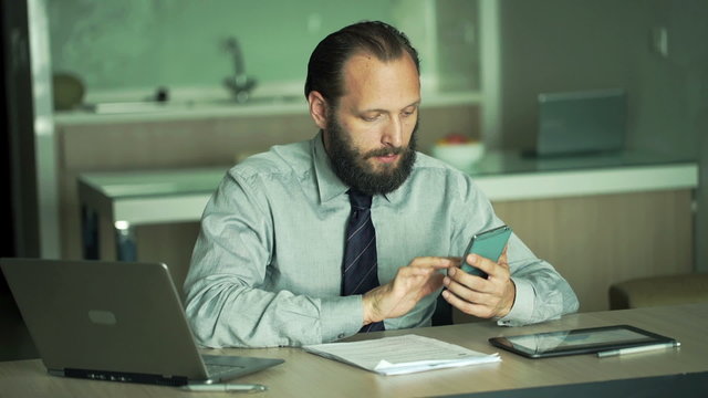 Young businessman working with smartphone and documents in office
