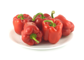 Five whole red ripe bell peppers isolated on white close up