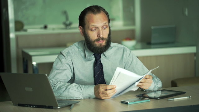 Unhappy businessman with tablet and laptop talking bad news in office
