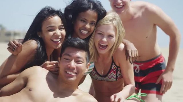 Group of interracial friends laughing together at the beach
