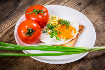 Fried egg on toast with greens and tomato