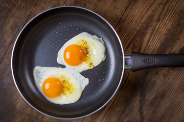 frying eggs in pan on wooden table